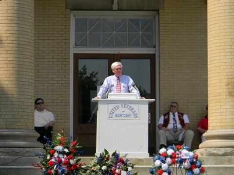 Image of speaker at a podium at top of Court House steps