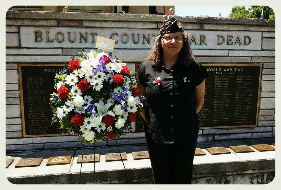 Woman standing beside wreath in front of war Memorial