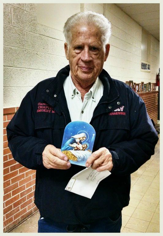 Standing veteran displays Mary and baby Jesus card to camera