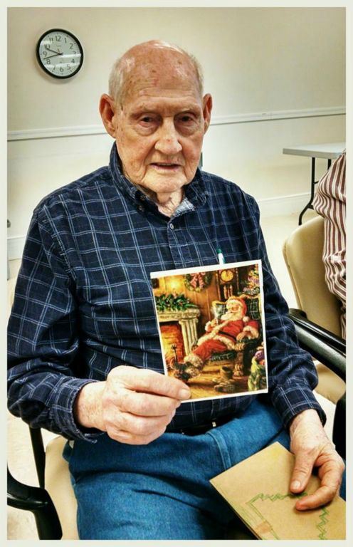 Man in blue shirt and jeans, sitting, holds up card for display