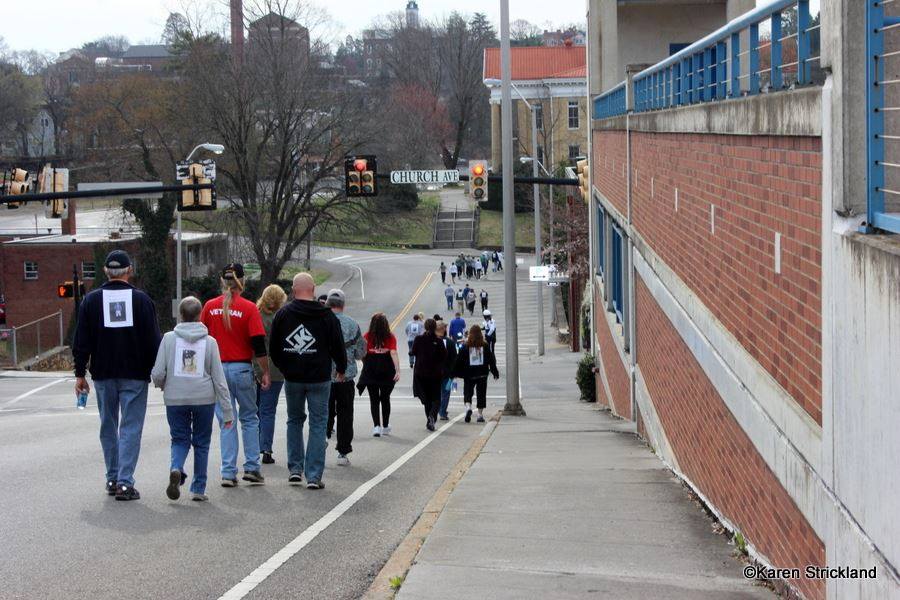 Trail of people walk on downward street