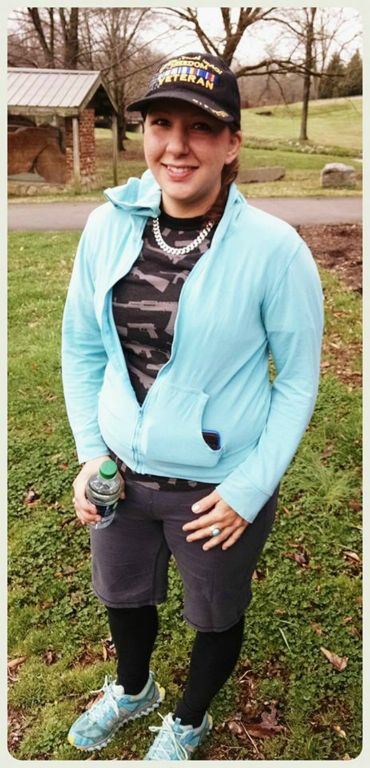 Woman in blue stands smiling at camera