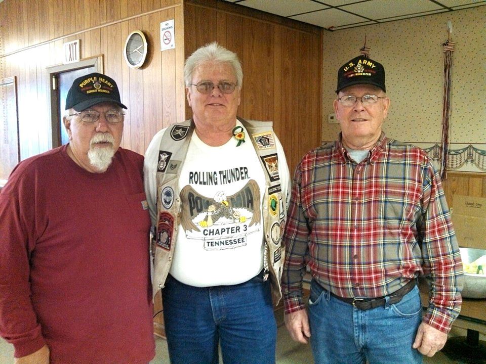 Three men stand together smiling at camera