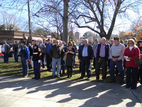 Crowd stands to one side of sidewalk