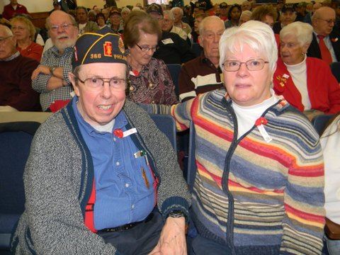 Two sitting participants, on in blue and one in multi-colored striped sweater, smile at camera