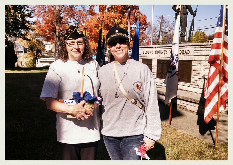 Two women smile and stand together otuside, one in veteran's cap