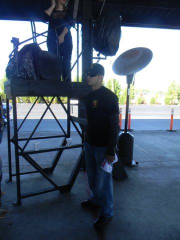 Side picture of man in jeans and black shirt with black hat under roof