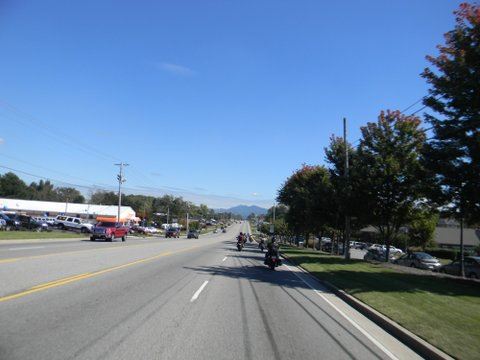 Picture taken from motorcycle of street with cars and bikes