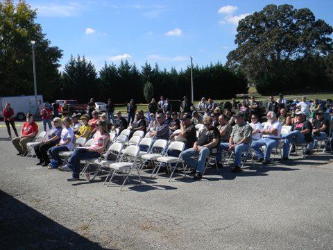 Sitting audience on cement listening to unpictured speaker